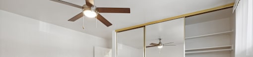 A room with a ceiling fan and a mirrored wall.