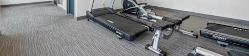 A gym with treadmills, weights, and exercise equipment.