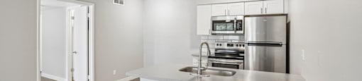 A modern kitchen with stainless steel appliances and white cabinetry.
