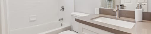 A white bathroom with a toilet, sink, and bathtub.