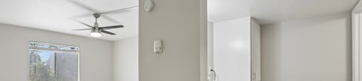 A room with a window, a ceiling fan, and a wall-mounted air conditioning unit.