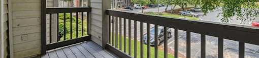 A balcony with a view of a street and trees.