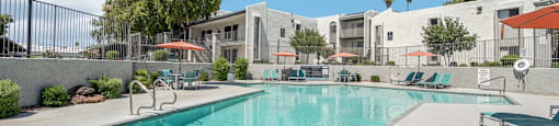A large swimming pool in front of a building with a fence around it.