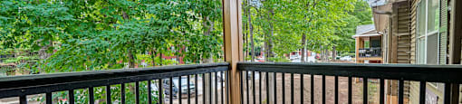 A balcony with a black railing and a wooden floor.