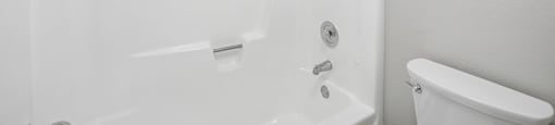 A white bathroom with a tub and toilet.