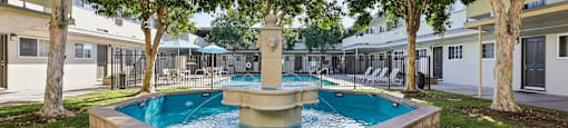 A small pool with a fountain in the middle of a courtyard.
