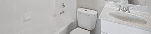 A white bathroom with a toilet, sink, and mirror.