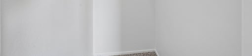 A white closet with a shelf and a carpeted floor.