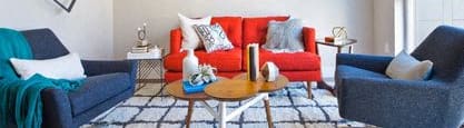 a living room with a red couch and two blue chairs