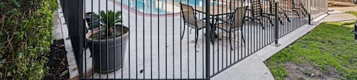 A pool surrounded by a black fence with a building in the background.