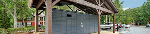 A wooden covered parking structure with a grey door.