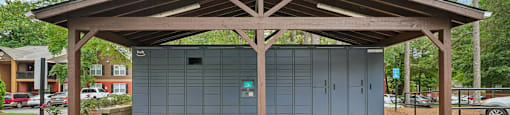 A wooden covered structure with a grey building behind it.
