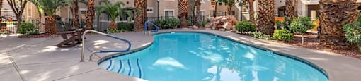 A pool surrounded by palm trees and a blue umbrella.
