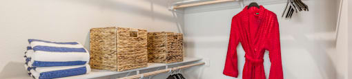 A red robe is hanging on a rack in a white closet.
