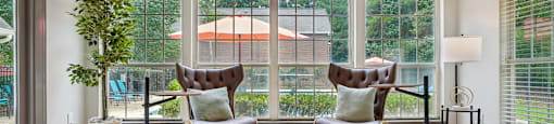 Two chairs are placed on a rug in a room with a large window.