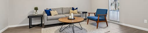 A living room with a grey couch, a blue chair, and a ceiling fan.