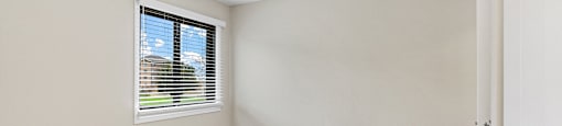 A room with a window and carpeted floor.