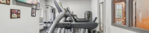 A gym with a treadmill and a painting on the wall.