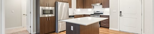 A modern kitchen with wooden floors and a central island.