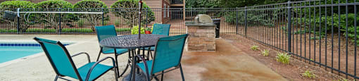 A patio with a table and chairs and an orange umbrella.