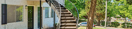A white house with a green railing on the stairs.