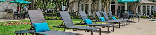 A row of blue and black lounge chairs are arranged on a patio.