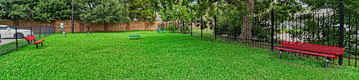 A park with a green lawn and a red bench.