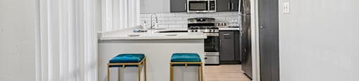 A kitchen with a bar stool in front of it.