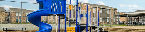 A playground with a blue slide and a yellow slide.