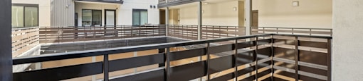 A balcony with a black railing and a concrete floor.