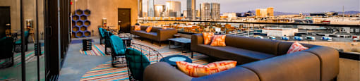 A rooftop patio with a view of the city skyline at dusk.
