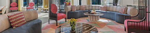 A modern living room with a glass table and a striped rug.