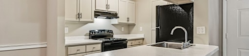 A kitchen with a white countertop and black appliances.