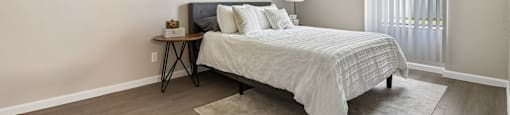 A bedroom with a bed, nightstand, and two pictures on the wall.