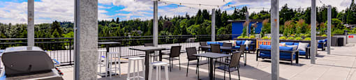 Dog Friendly Apartments in Bothell, WA - 98th Avenue - An exterior shot of the community rooftop lounge, featuring plush seating, tables, and aesthetic lighting