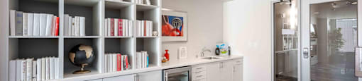 a living room with white cabinets and bookshelves and a glass door