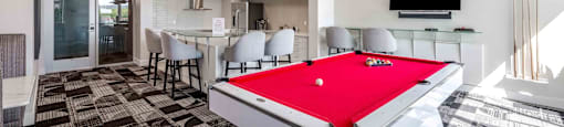 a red pool table in a room with a bar and a television
