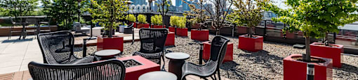 a rooftop patio with tables and chairs and trees