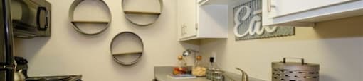 Dog Friendly Apartments in Mesa AZ - Mesa Station - Kitchen with Grey Speckled Countertops, White Upper Cabinetry, Grey Lower Cabinetry, Black Appliances, and Wood-Style Flooring