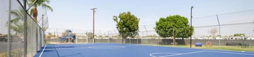 a blue tennis court with trees in the background