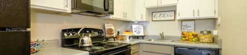 Apartments for Rent Mesa, AZ - Mesa Station - L-Shaped Kitchen with White and Grey Cabinetry, Black Appliances, and Granite-Style Countertops