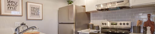 2-Bedroom Apartments in North Mountain Village, Phoenix, AZ - Ardella on 28th - Modern Kitchen with Stainless Steel Appliances, White Cabinetry, Grey Tile Backsplash, and White Counters