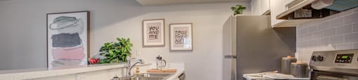 Three Bedroom Apartments in Phoenix, AZ - Adrella on 28th - Kitchen with White Countertops, Stainless Steel Appliances, and Track Lighting.