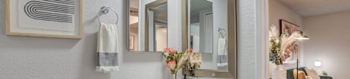 a bathroom with a sink and three mirrors on the wall