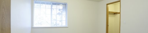 A room with a carpeted floor, a window, and a door.