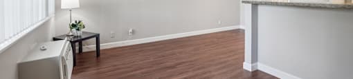 an empty living room with a kitchen and a ceiling fan