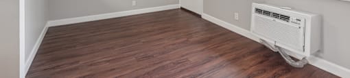 an empty living room with wood flooring and a large window