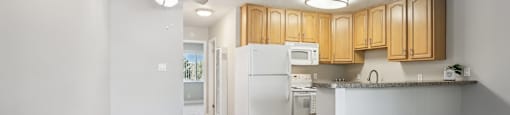 an empty living room and kitchen with wood floors and white appliances