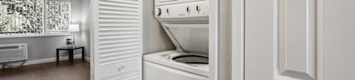 a small kitchen with white appliances and a door to the laundry room