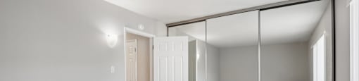 an empty bedroom with mirrored closet doors and a carpeted floor